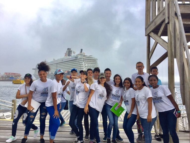 Group in matching shirts on the pier with a cruise ship behind them