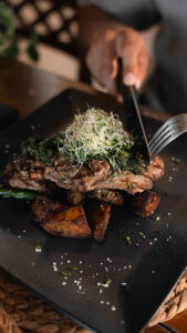 Grilled meat with chimichurri and roasted potatoes being served