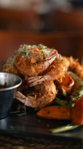 Stacked coconut shrimp with sprouts and roasted vegetables
