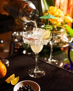Bartender pouring a freshly shaken margarita into a salt rimmed glass