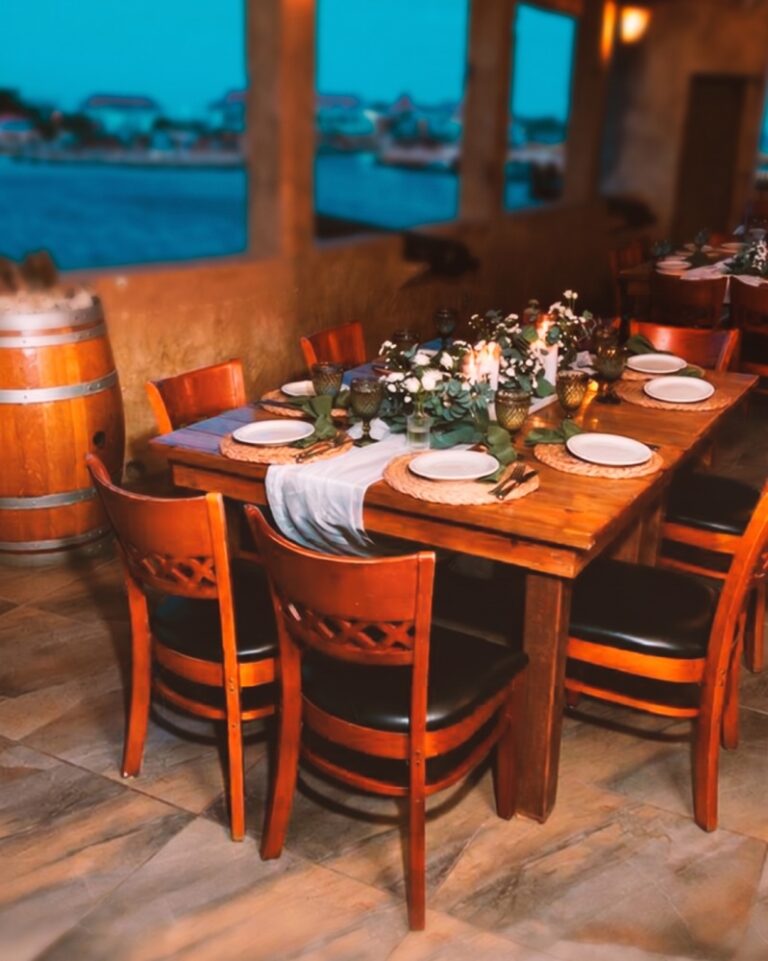 Table set for dinner on the terrace at dusk, with the harbour beyond
