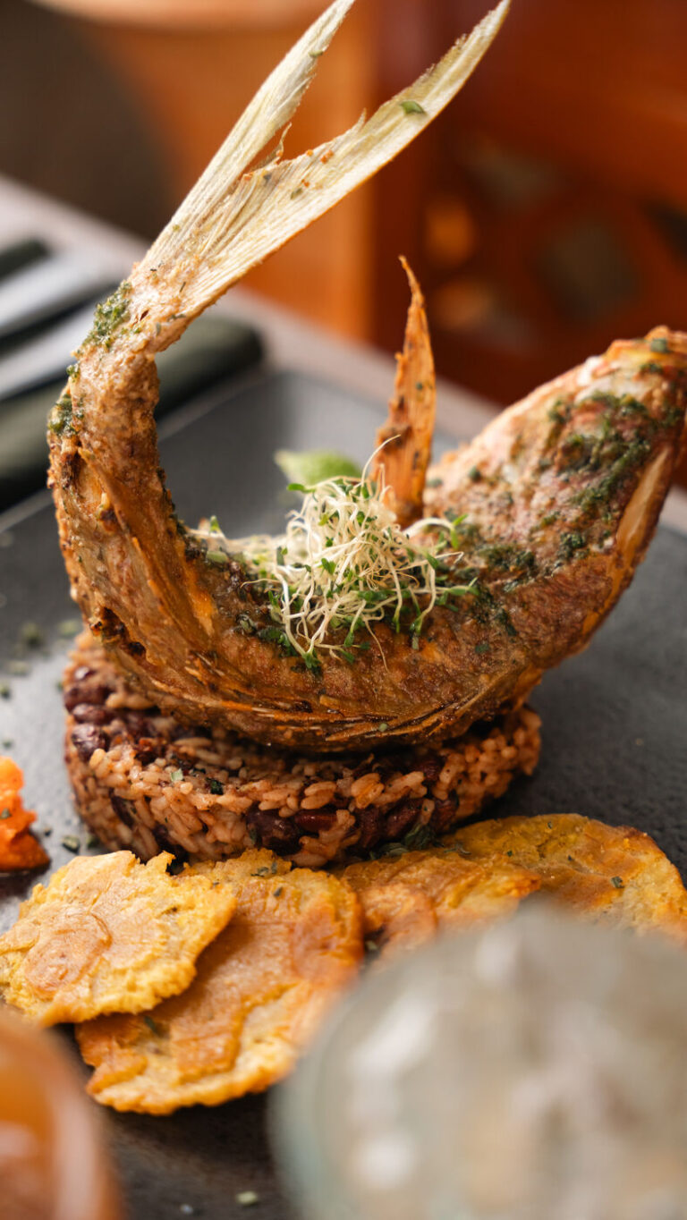 Fried whole fish with herb crust, served with rice and beans and tostones