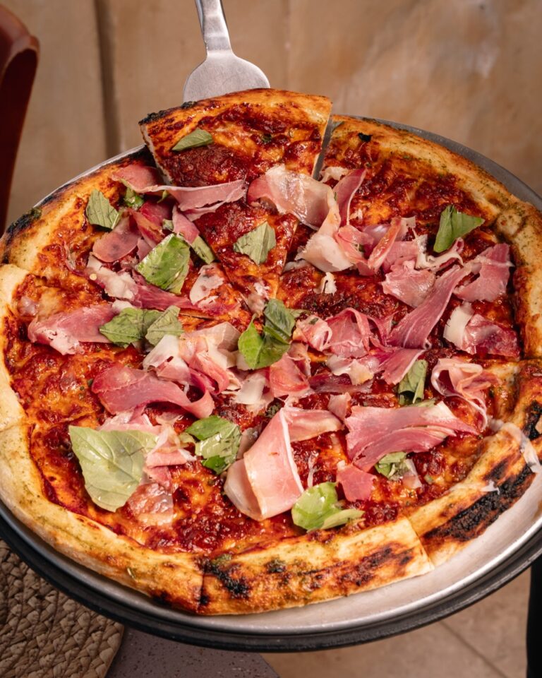 Pizza topped with prosciutto, fresh basil and hot honey
