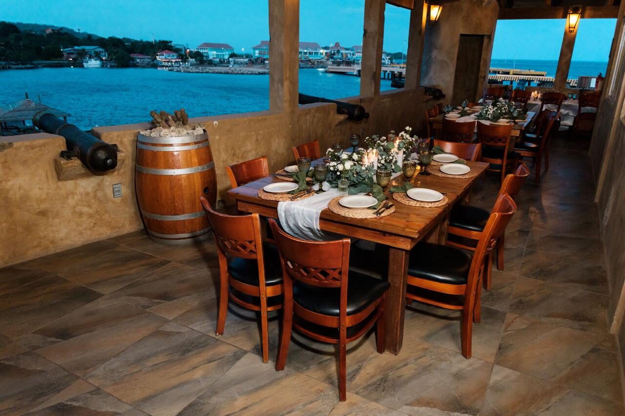 Long table set for a private event at Fort Consolation, with the sea and a cannon in view