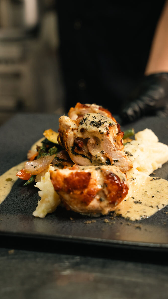 Herby chicken breast stuffed with bacon, spinach and cheddar, with cream sauce and vegetables
